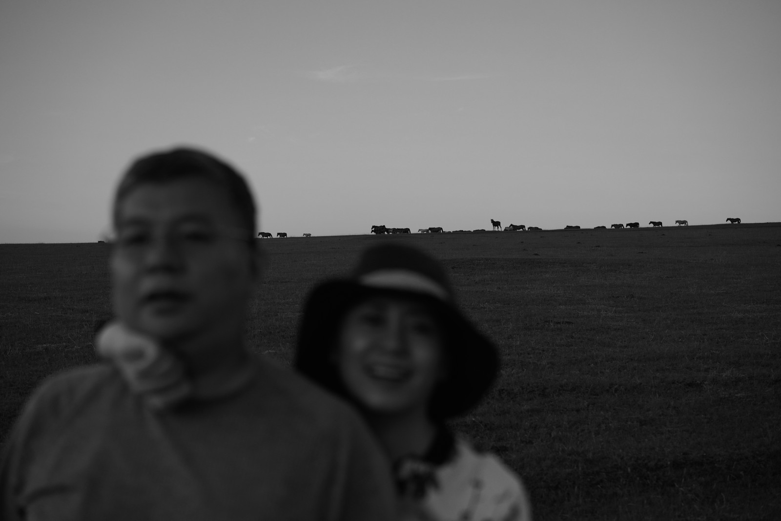 A black and white portrait of two people in a grassy field.