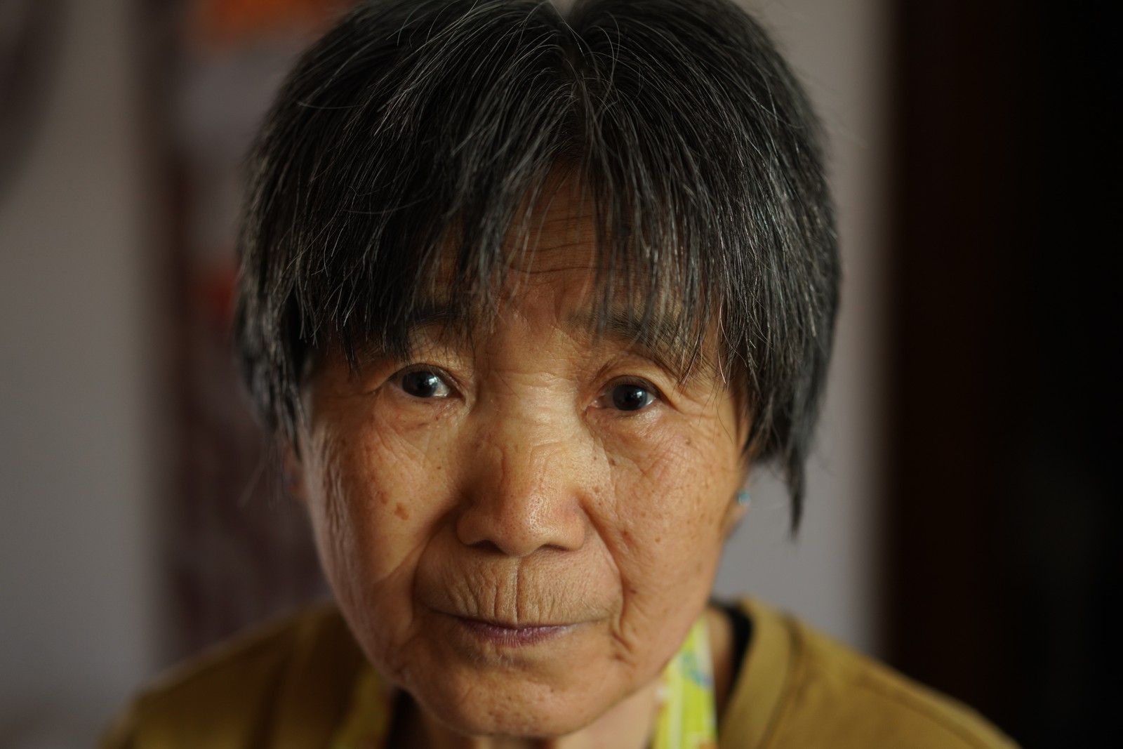 A close portrait of a person in a mustard-colored shirt.