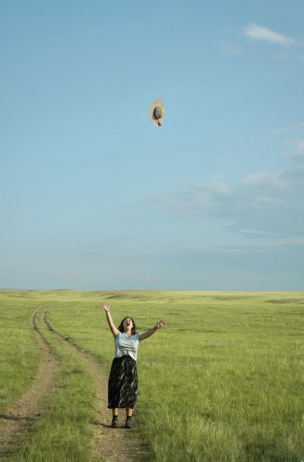 A person walking between fields beneath an open sky.