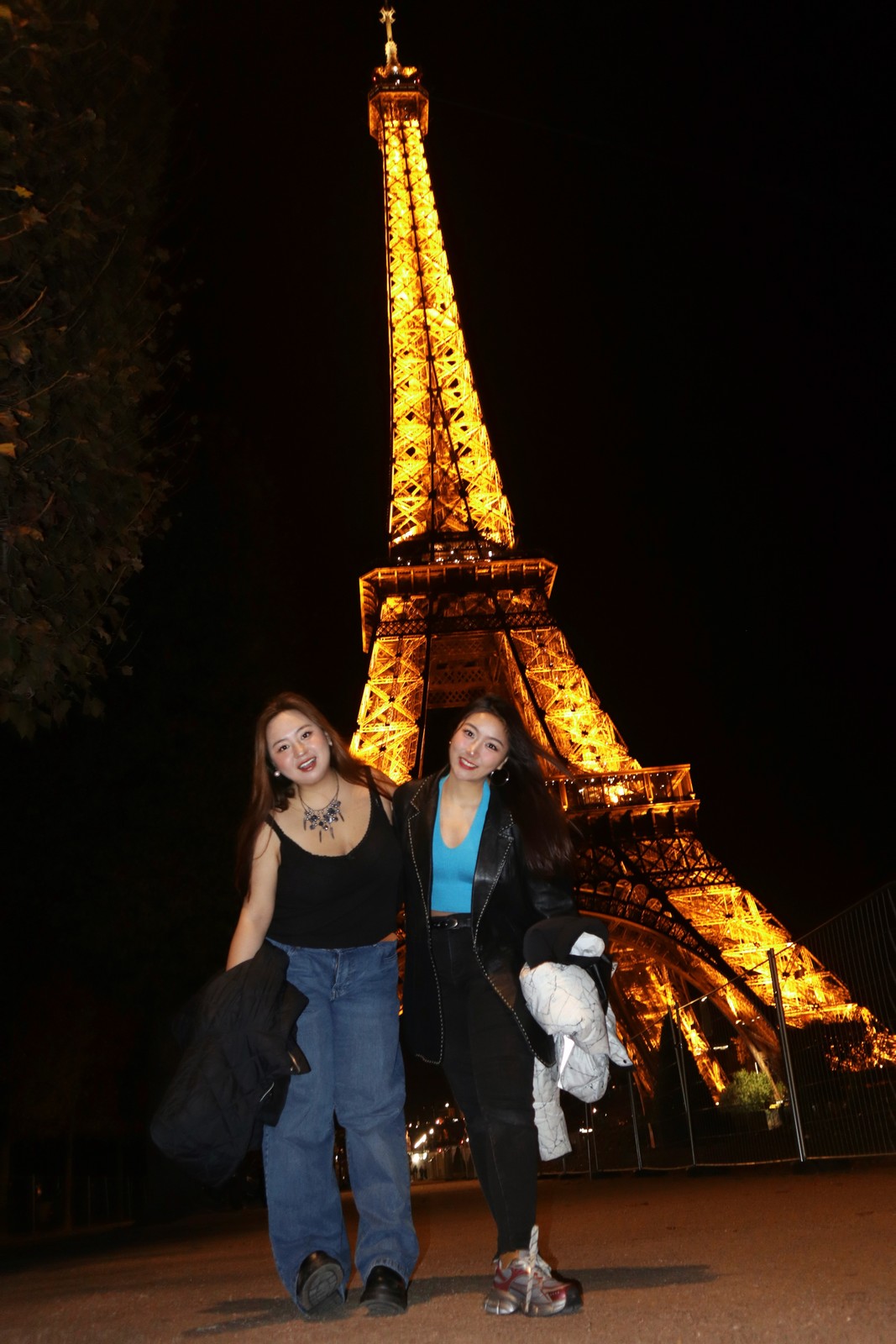 A person beneath the illuminated Eiffel Tower at night.