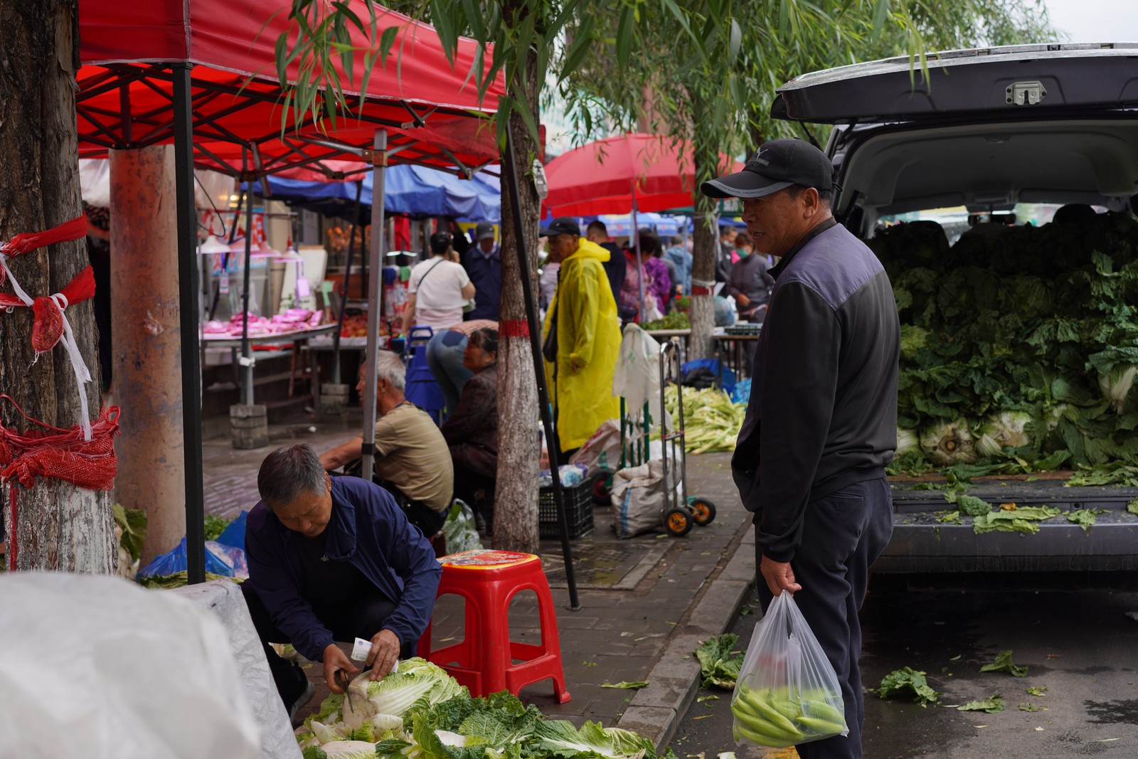 People gathering at an outdoor market beneath red canopies.