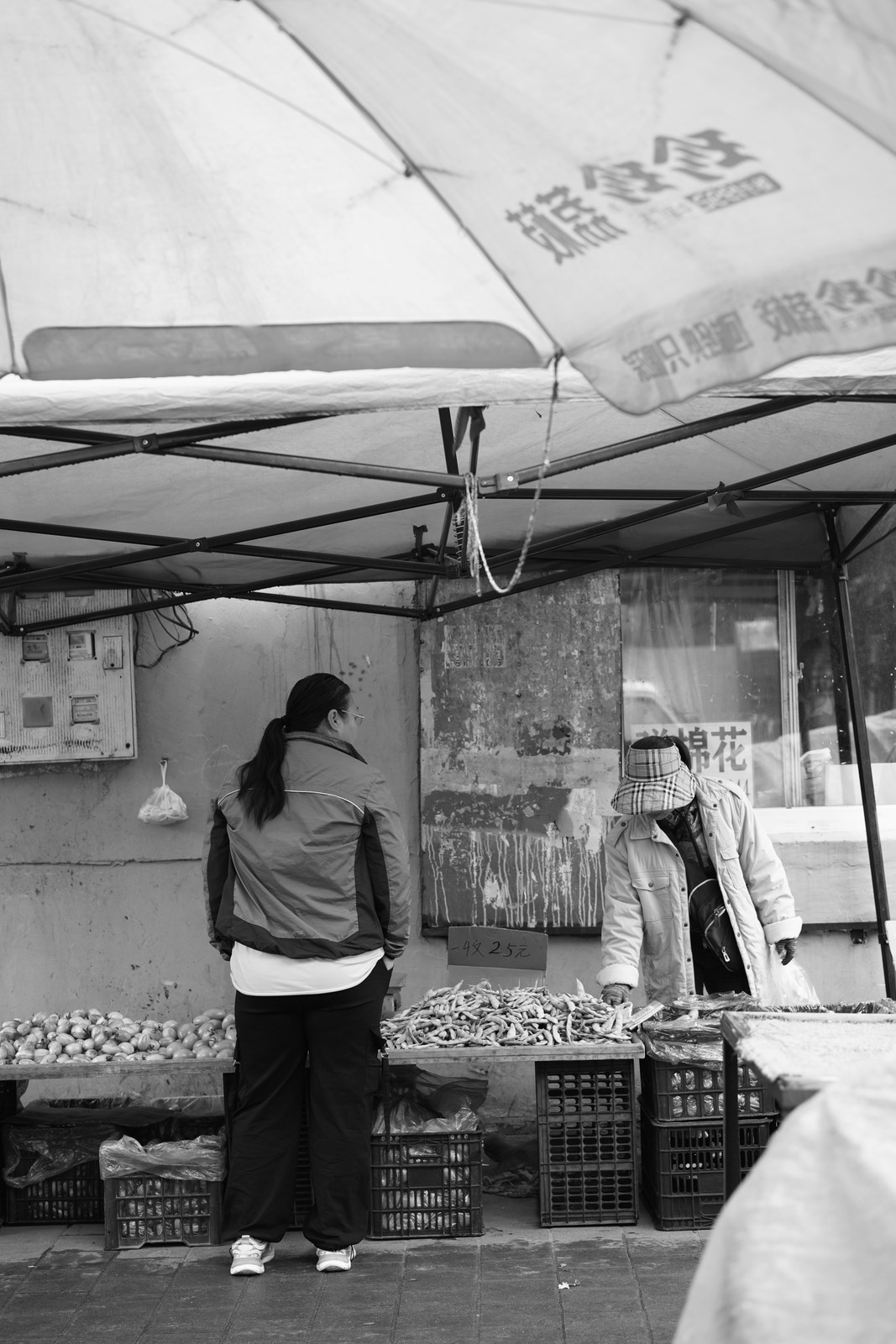 A black and white photograph of a person working at a market stall.
