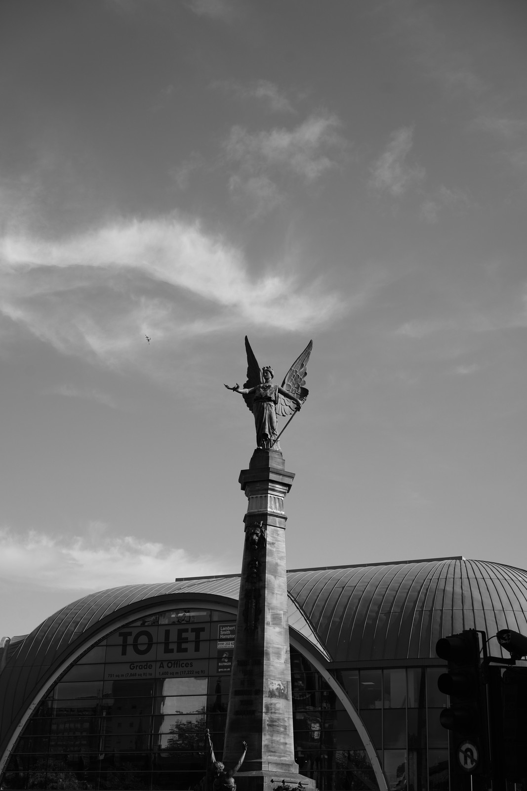A black and white view of a utility pole and a city building.